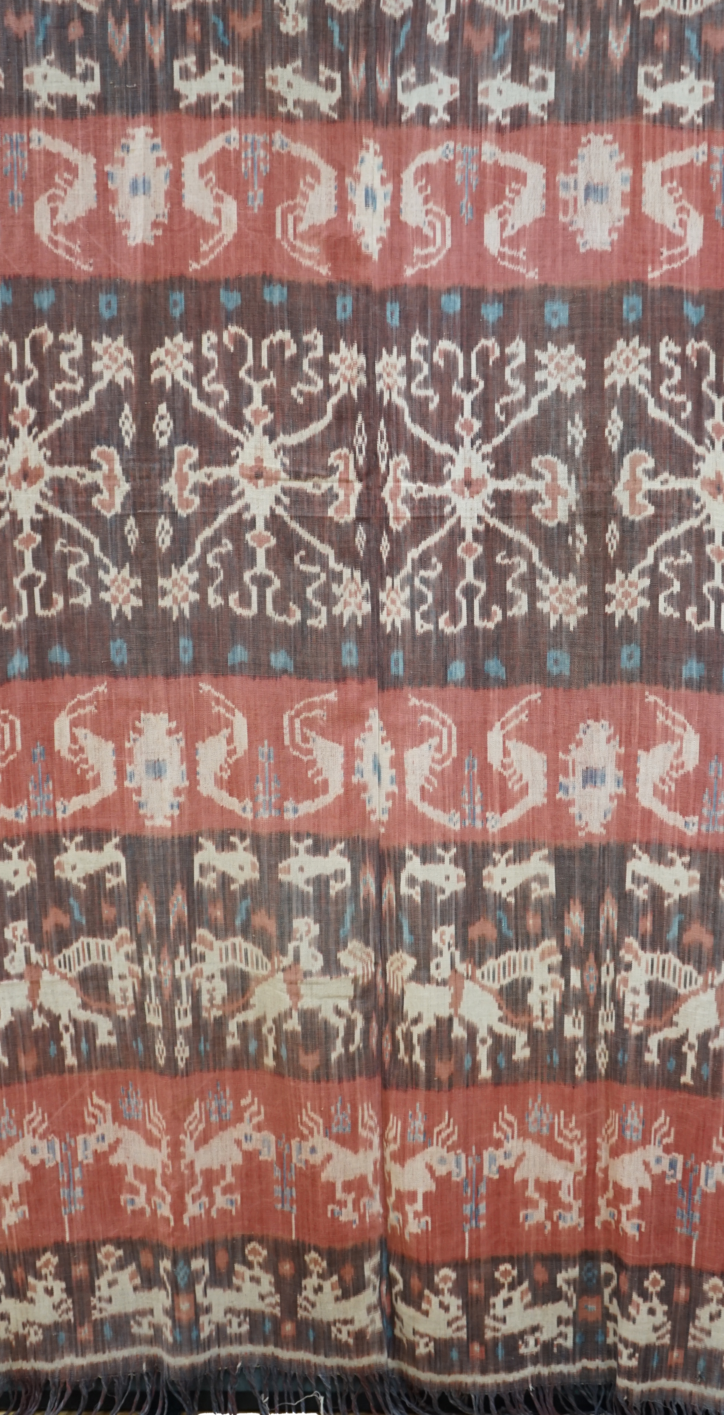 A hand woven hand dyed Ikat Sumbanese Hinggi (shoulder cloth), together with an Indian chain stitch embroidered panel, the Hinggi woven on two short 56cm wide looms sewn together forming horizontal bands, depicting men o